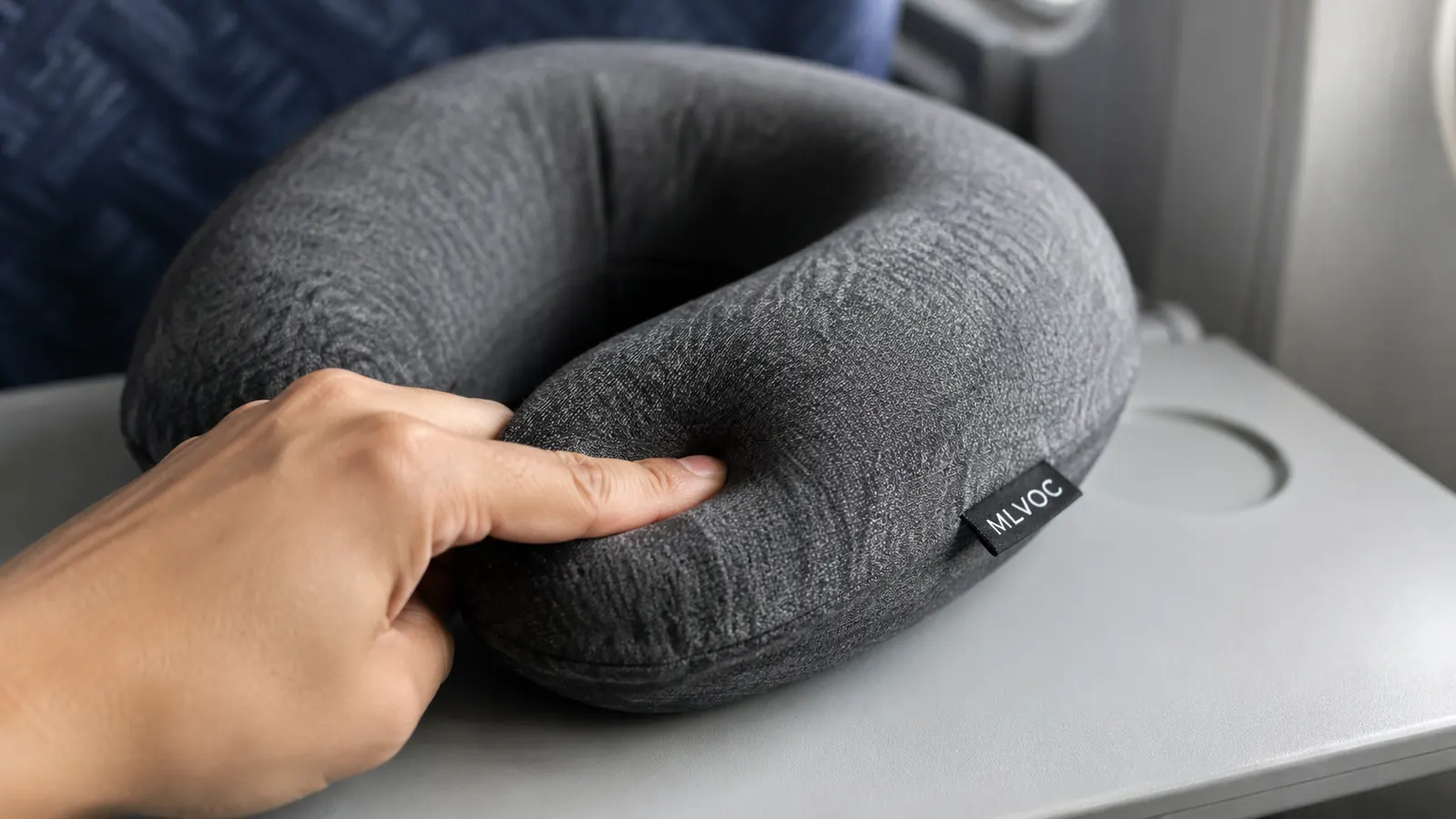 Hand pressing into the memory foam of the MLVOC neck pillow to show slow-recovery foam density